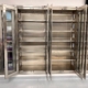 Empty stainless steel storage cabinet with glass double doors, standing on a smooth gray floor against a light beige wall. The cabinet features multiple adjustable shelves and a clean, modern design with a brushed metal finish